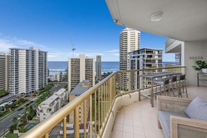 Un balcon offrant une vue sur l’océan et les grands immeubles environnants.