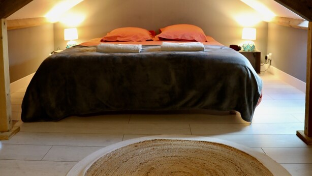 Une chambre à coucher avec un lit, un tapis rond et des poutres en bois au plafond.