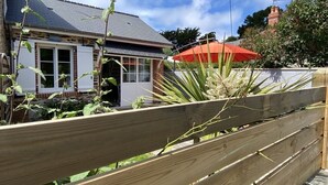 Une clôture en bois, une maison avec un parasol rouge et un moulin à vent en arrière-plan.