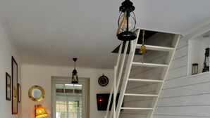 Un salon moderne avec un canapé bleu, une table à manger et des chaises, un escalier et une lampe.