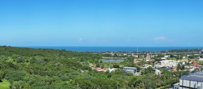 A coastal town with dense greenery, a lake, and buildings with solar panels. - I need motel (Xinfeng)