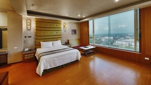 A spacious hotel room with a large bed, a wooden floor, a view of the city through large windows, and a modern ceiling design. - I need motel (Xinfeng)