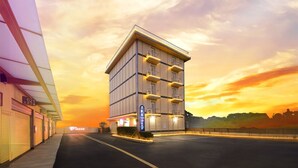 A multi-story hotel with a modern design, featuring balconies and a parking area. - I need motel (Xinfeng)