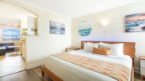Une chambre d’hôtel avec un grand lit, un bureau et une vue sur l’océan.