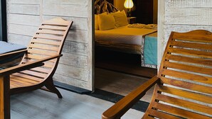 A room with wooden walls, a bed with yellow bedding, and two wooden chairs. - Sigiri Vananthara  (Habarana)