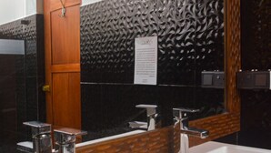 Un baño con un espejo grande, una puerta de madera y un lavabo con detalles cromados.
