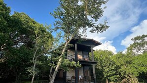 A two-story wooden cabin with a balcony, surrounded by lush greenery and trees. - Sigiri Vananthara  (Habarana)