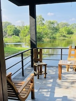 Una terraza de madera con una mesa y sillas que da a un cuerpo de agua y follaje.