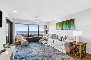 A modern living room with a large window, a white sofa, a side table, and a decorative lamp.