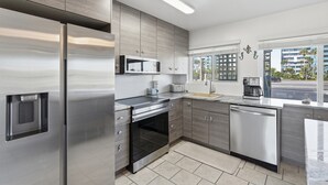 Cozinha moderna com eletrodomésticos de aço inoxidável, micro-ondas e máquina de lavar louça.