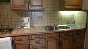 Una cocina con gabinetes de madera, un lavamanos, una estufa y una cafetera.