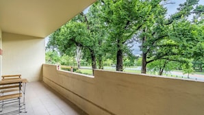 Uma varanda com vista para árvores verdes e uma estrada. Há bancos ao longo da varanda.