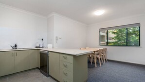 Uma cozinha compacta com máquina de lavar louça, bancada pequena e área de refeições com mesa e cadeiras.