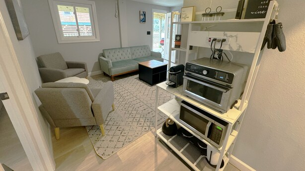 A modern living room with a sofa, a coffee machine, and a neon sign. - SeaSide Serenity - Cozy Retreat on Bay Drive (Kill Devil Hills)
