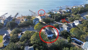 An aerial view of a coastal residential area with houses, a dock, and a public access point circled. - SeaSide Serenity - Cozy Retreat on Bay Drive (Kill Devil Hills)