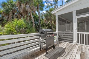 Une terrasse extérieure dotée d’un barbecue, d’une rambarde blanche et d’un espace abrité avec des fenêtres.