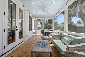 A covered outdoor patio with wicker furniture, a ceiling fan, and a view of the surrounding landscape.