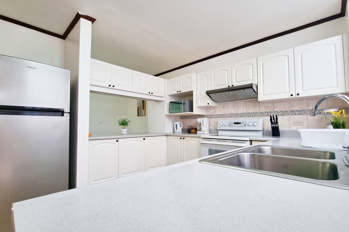 A modern kitchen with white cabinets, stainless steel appliances, and a central island with a sink.