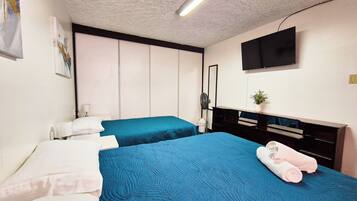 Een hotelkamer met twee bedden, een flatscreen-tv, een bureau en een spiegel.