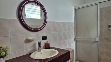 Ein Badezimmer mit Waschbecken, Spiegel und Dusche.