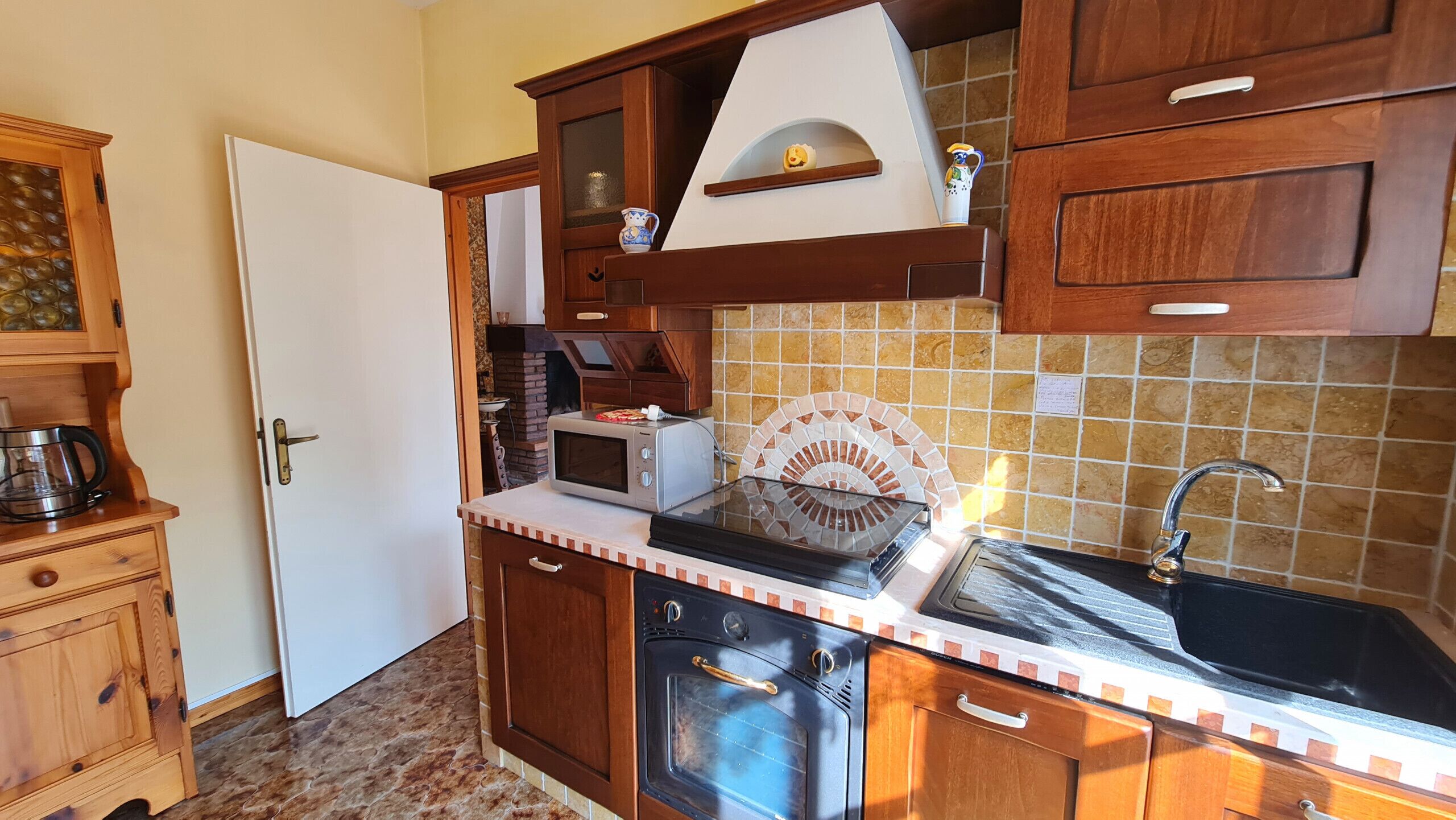A compact kitchen with wooden cabinets, a microwave, a toaster, and a sink.