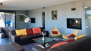 Ein modernes Wohnzimmer mit einer Couch, Sesseln, einem Couchtisch und einem Kamin.