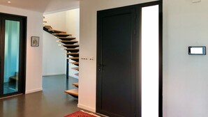 Ein modernes Interieur mit Treppe, einer dunklen Tür und heller Wand.