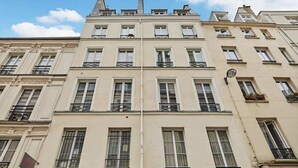 A multi-story building with a symmetrical facade, featuring evenly spaced windows and balconies with wrought iron railings. - Apartment  Center of Paris (Paris)
