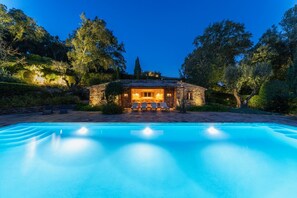 Ein Pool mit einem Haus aus Stein im Hintergrund.