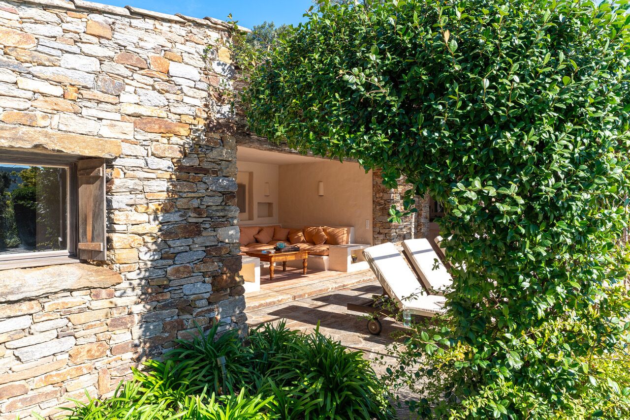 A stone building with a patio area featuring a sofa and a table.
