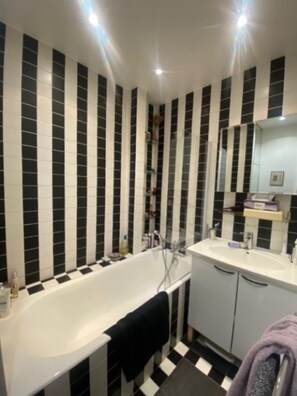 Bathroom features a bathtub, sink, and mirror.