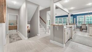 Une cuisine spacieuse dotée d’un îlot central, un coin repas avec une table et des chaises, et un escalier menant à un autre niveau.