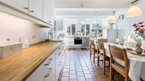 A modern kitchen with white cabinets, a wooden countertop, and a dining area with a table and chairs.