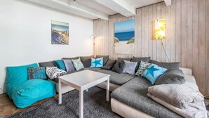 A modern living room with a sectional sofa, a coffee table, and two wall-mounted lamps.