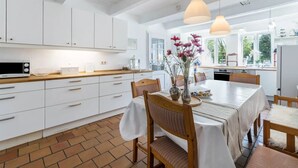 A modern kitchen with white cabinets, a wooden countertop, and a dining area with a table set for four.