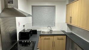 A compact kitchen with a stove, sink, and wooden cabinets.