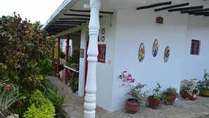 A white building with a stone-paved entrance, potted plants, and a column.