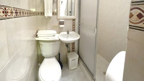 A bathroom with a toilet, sink, and shower.