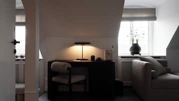 A modern loft bedroom with a desk, chair, and a large window.