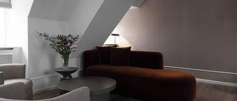 Una sala moderna con un sofá seccional, una mesa redonda de centro y un jarrón con flores.