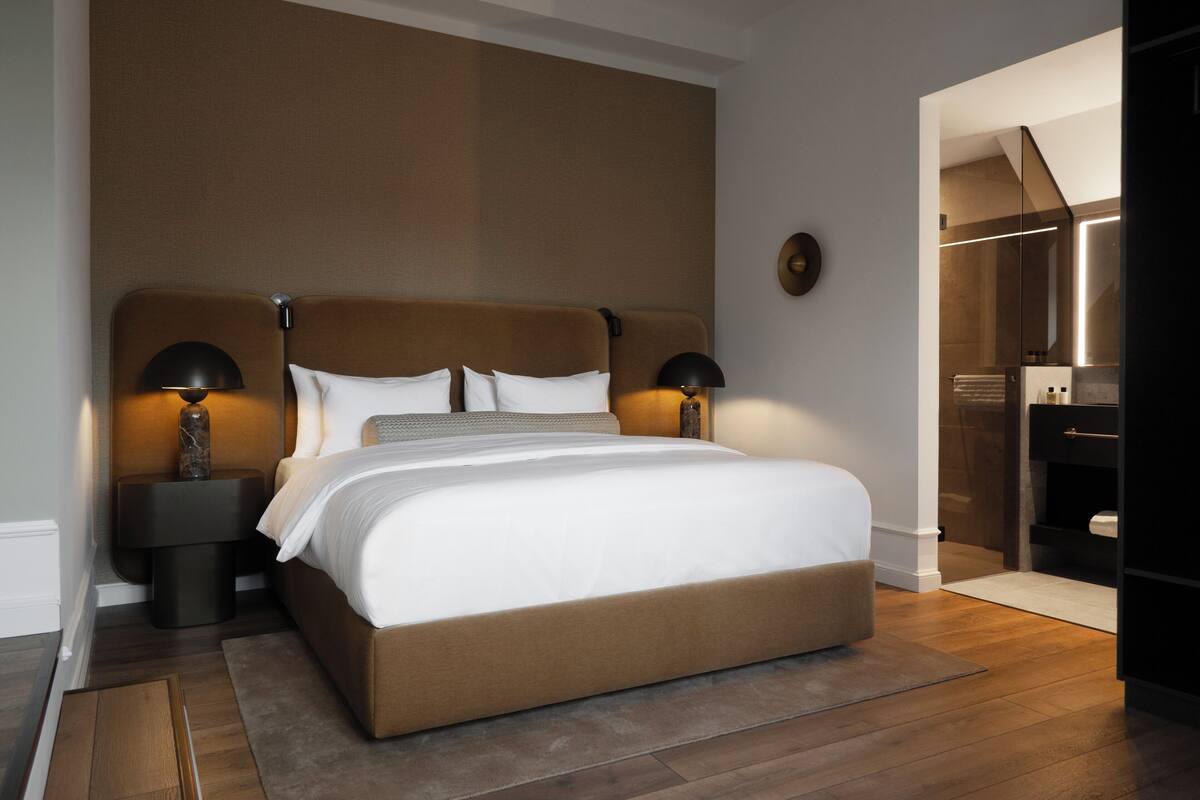 Un dormitorio moderno con una cama grande, dos lámparas de noche y una mesita de noche.