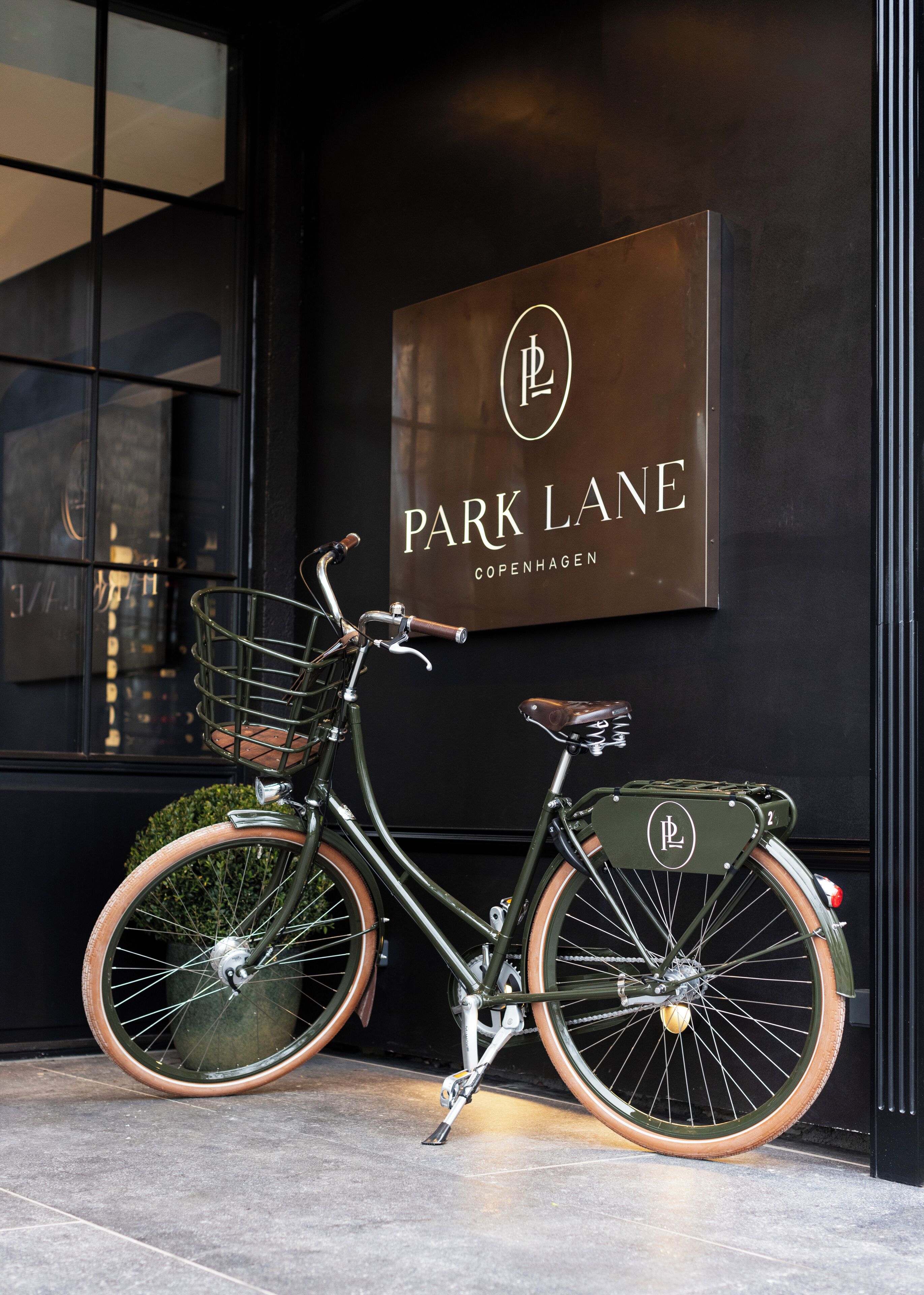 Una bicicleta estacionada frente a un edificio con un letrero que dice "Park Lane Copenhagen".