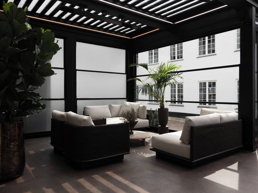 Ein moderner Außenbereich zum Sitzen mit schwarzen und weißen Sofas, einem Couchtisch und Topfpflanzen.