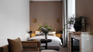 Una habitación de hotel moderna con una cama, un sofá, una mesita y una chimenea.