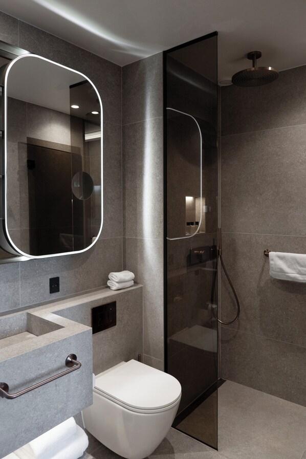 A modern bathroom with a glass-enclosed shower, a large mirror, and a built-in toilet.