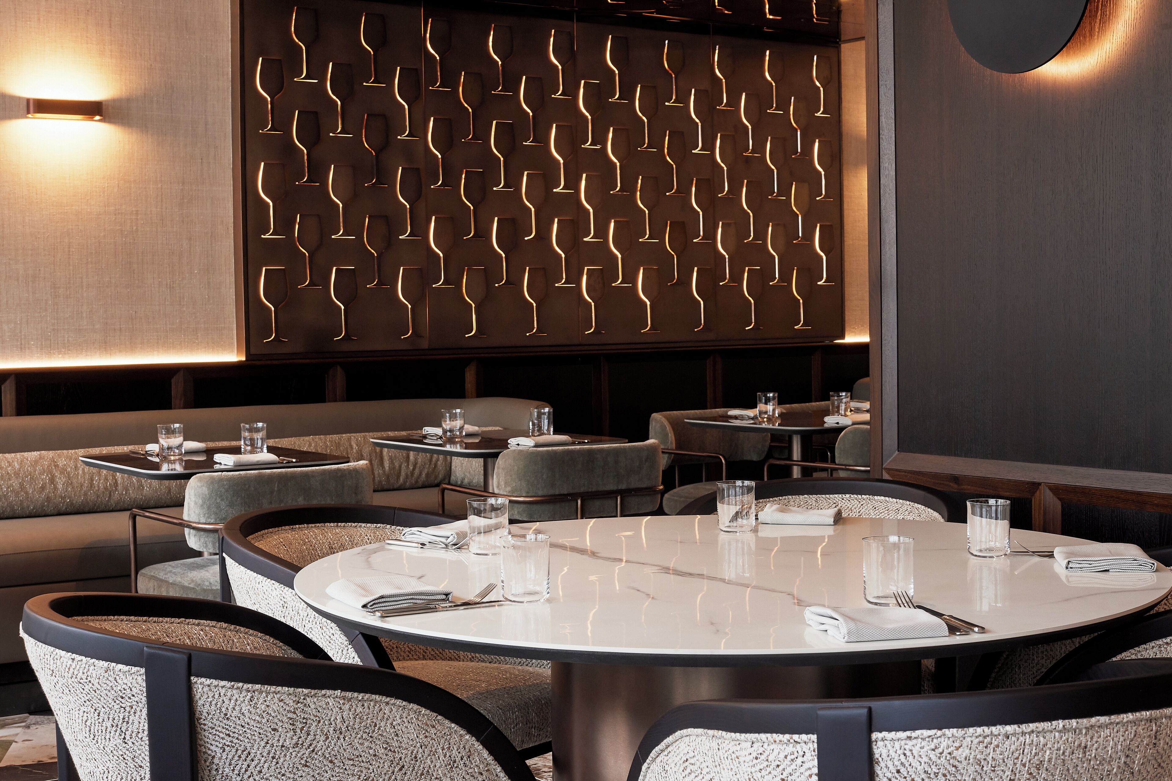 Un ristorante moderno con tavoli rotondi, sedute imbottite e un decoro murale a motivi.