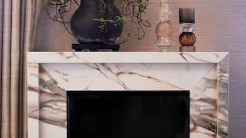 A fireplace with a marble surround, a potted plant, and decorative items on the mantel.