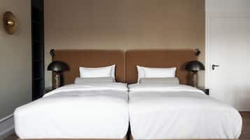A double bed with white linens, two bedside lamps, and a brown headboard in a hotel room.