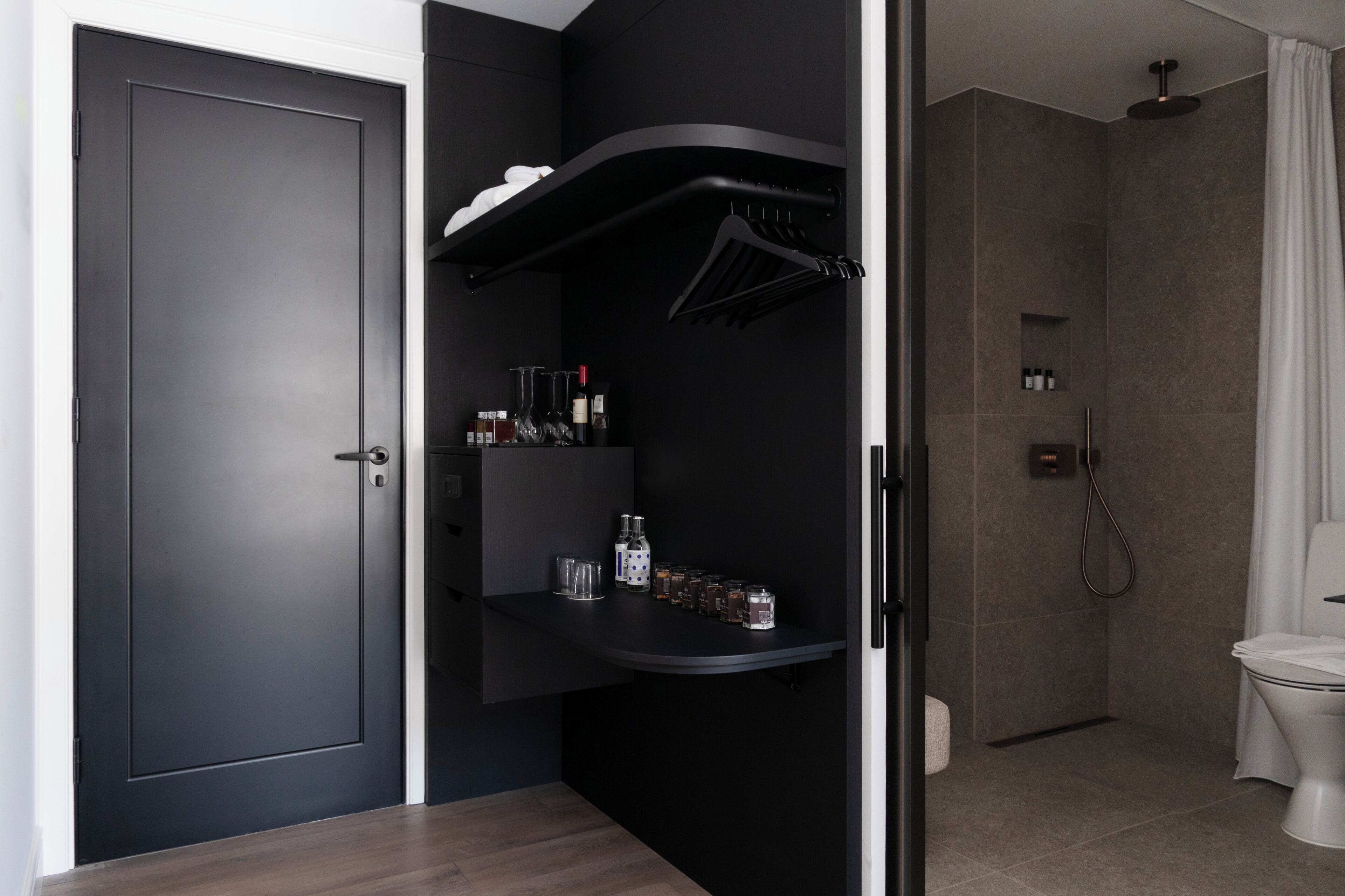A modern bathroom with a dark wall, a shower, and a toilet.