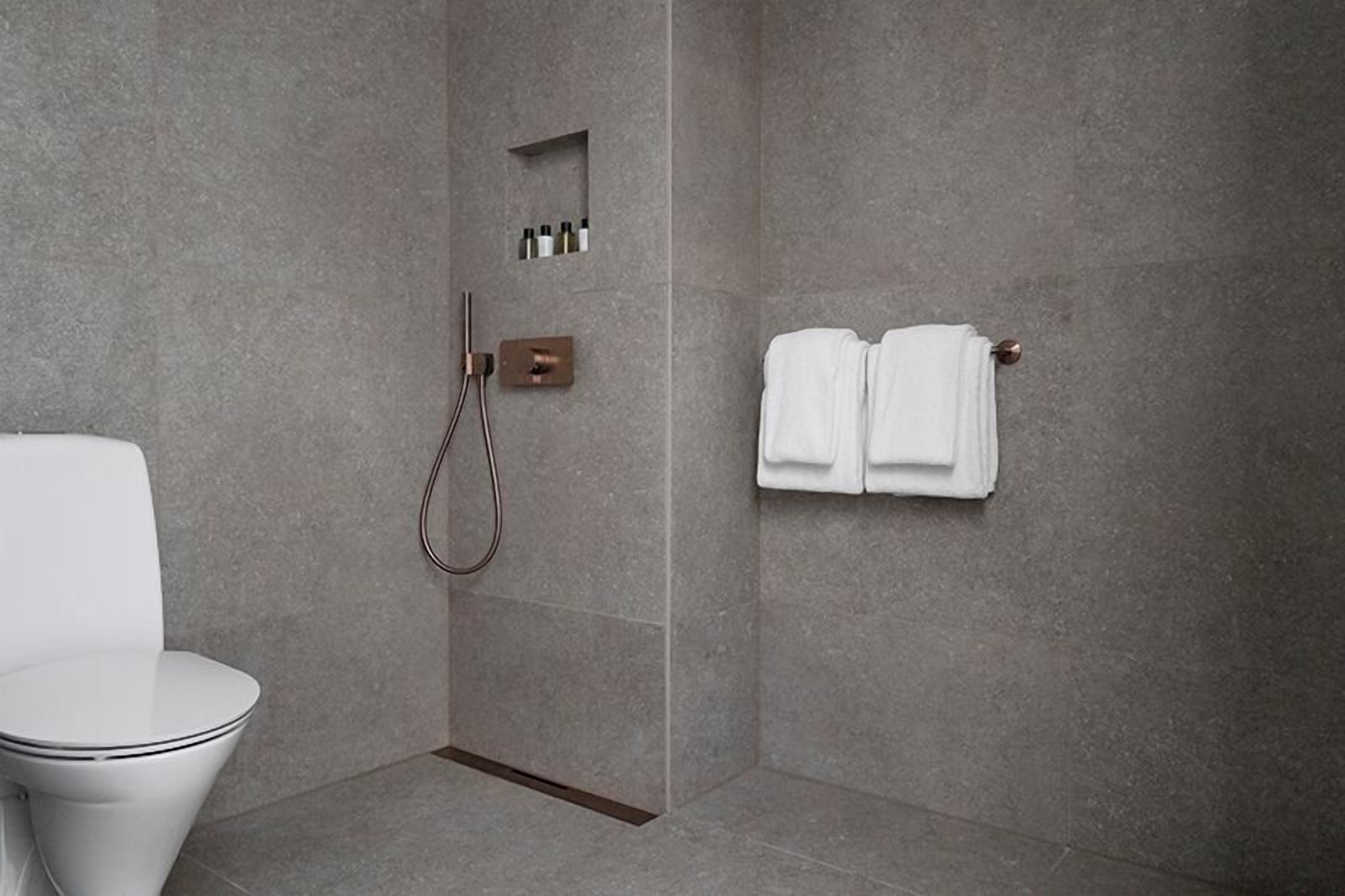 A modern bathroom with a shower, toilet, and towel rack.